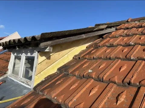 Rive de toiture et lucarne en cours de reprise, bardage bois neuf sous la rive
